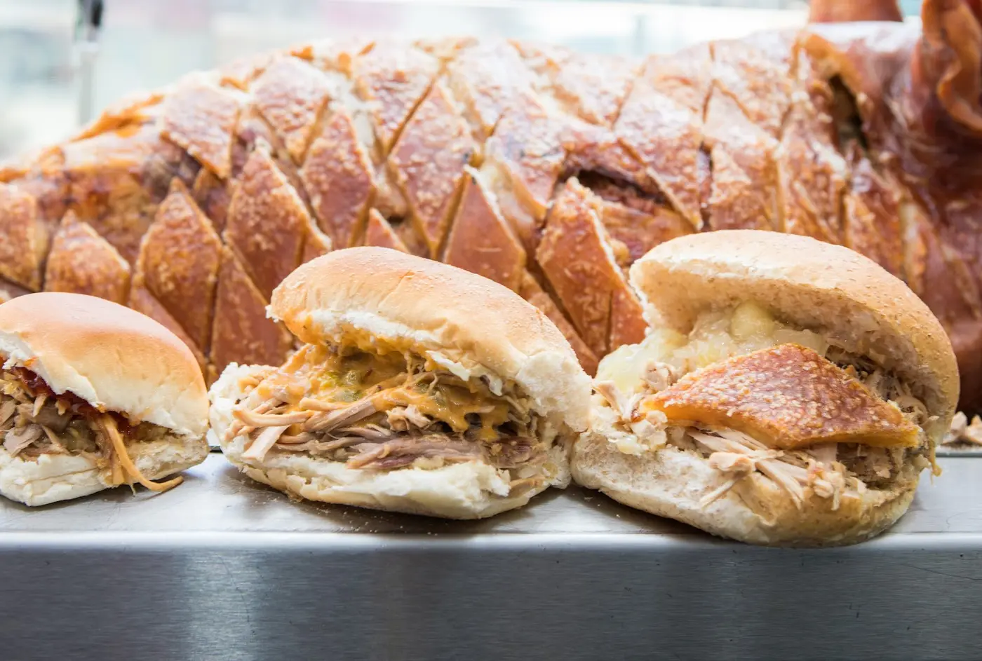 Three hog roast rolls in front of the whole roasted hog at Oink Victoria Street